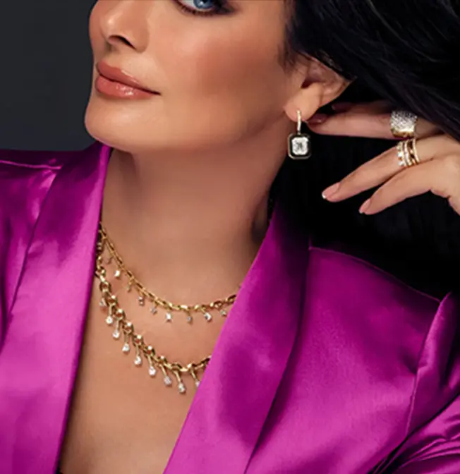 A woman wearing a purple jacket and gold jewelry.