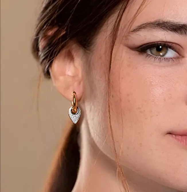 A woman with long brown hair wearing earrings.